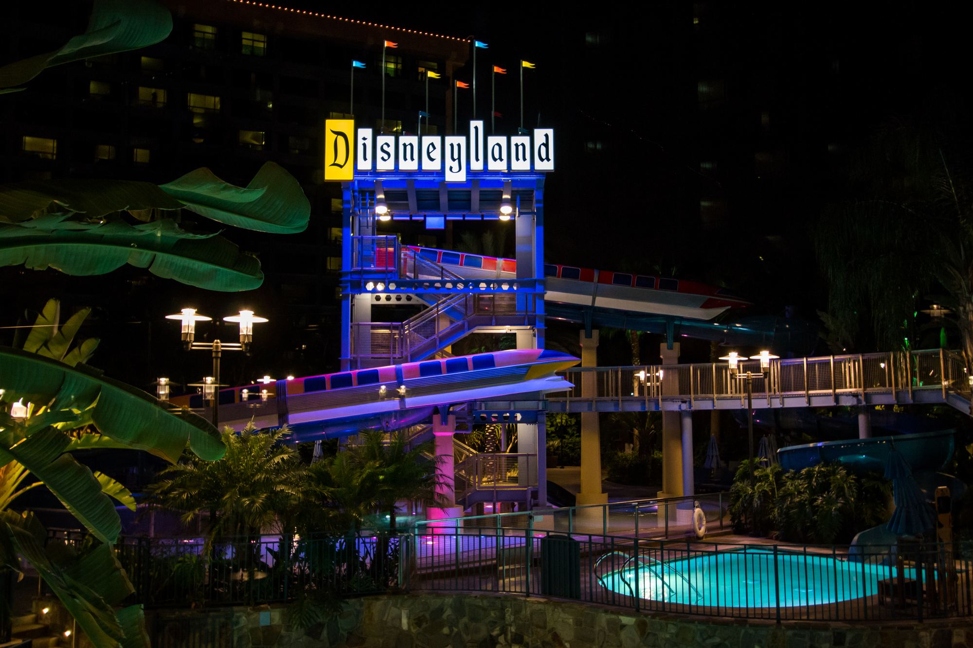 The Disneyland Hotel pool at night, with its waterslide under the lit Disneyland sign