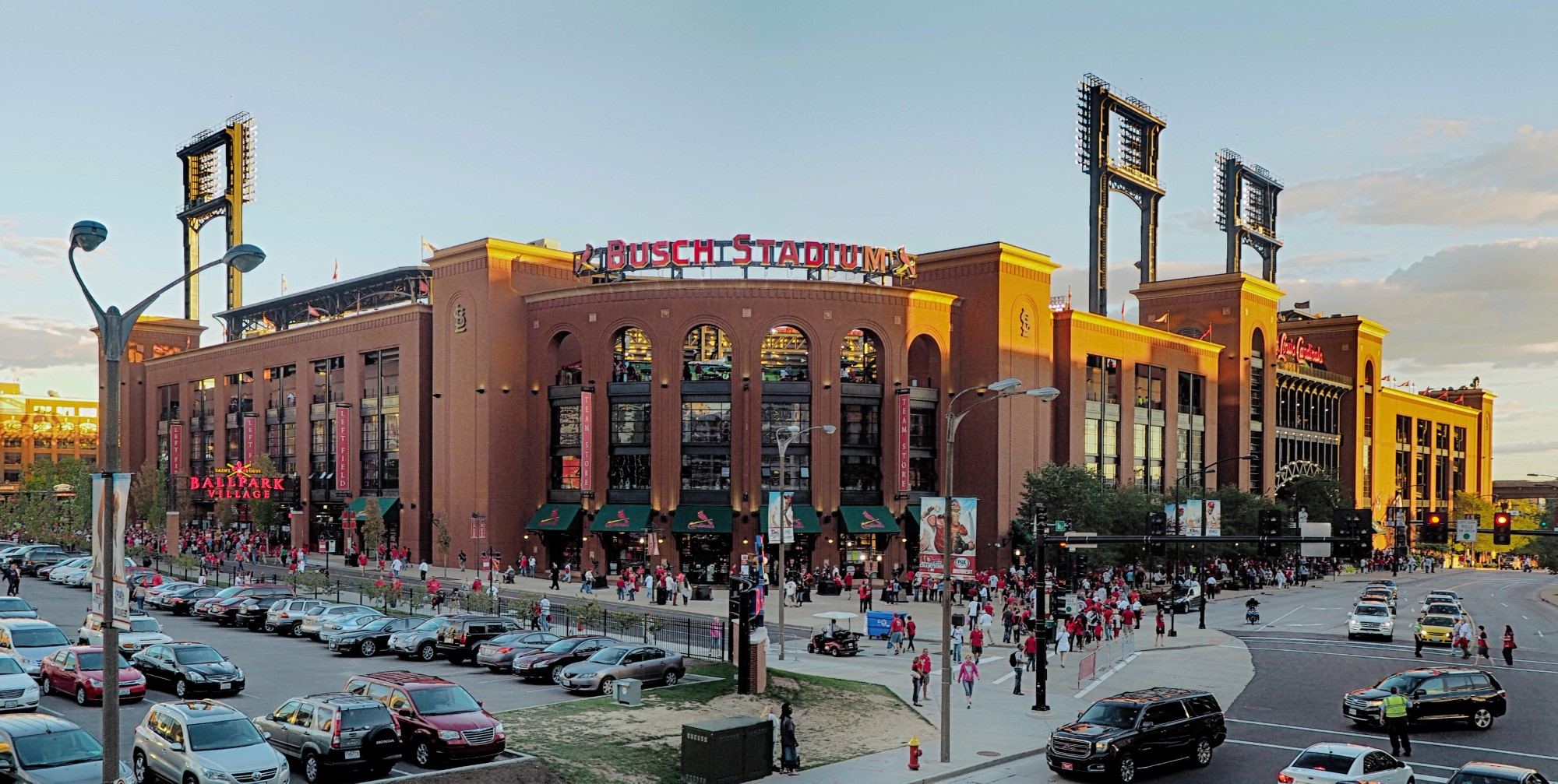 The brick exterior of Busch Stadium on a game day, with cars parked in the lot out front