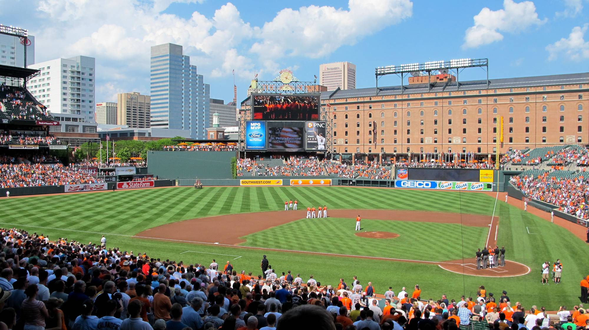 Oriole Park at Camden Yards with the open-air bowl, the long brick B&O Warehouse beyond right field, and the Eutaw Street promenade