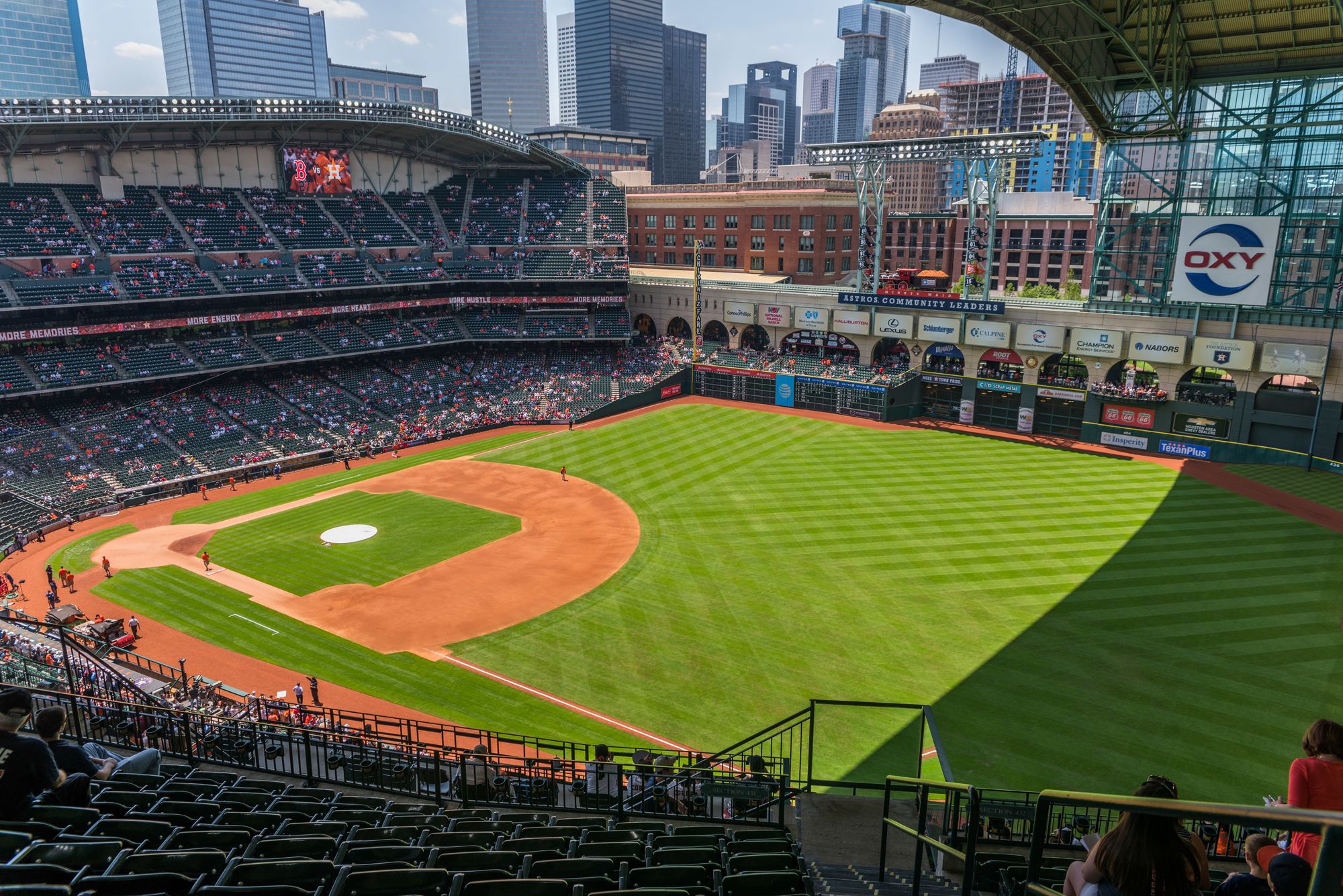 The field at Daikin Park from the upper deck, with the roof open and the downtown Houston skyline beyond left field