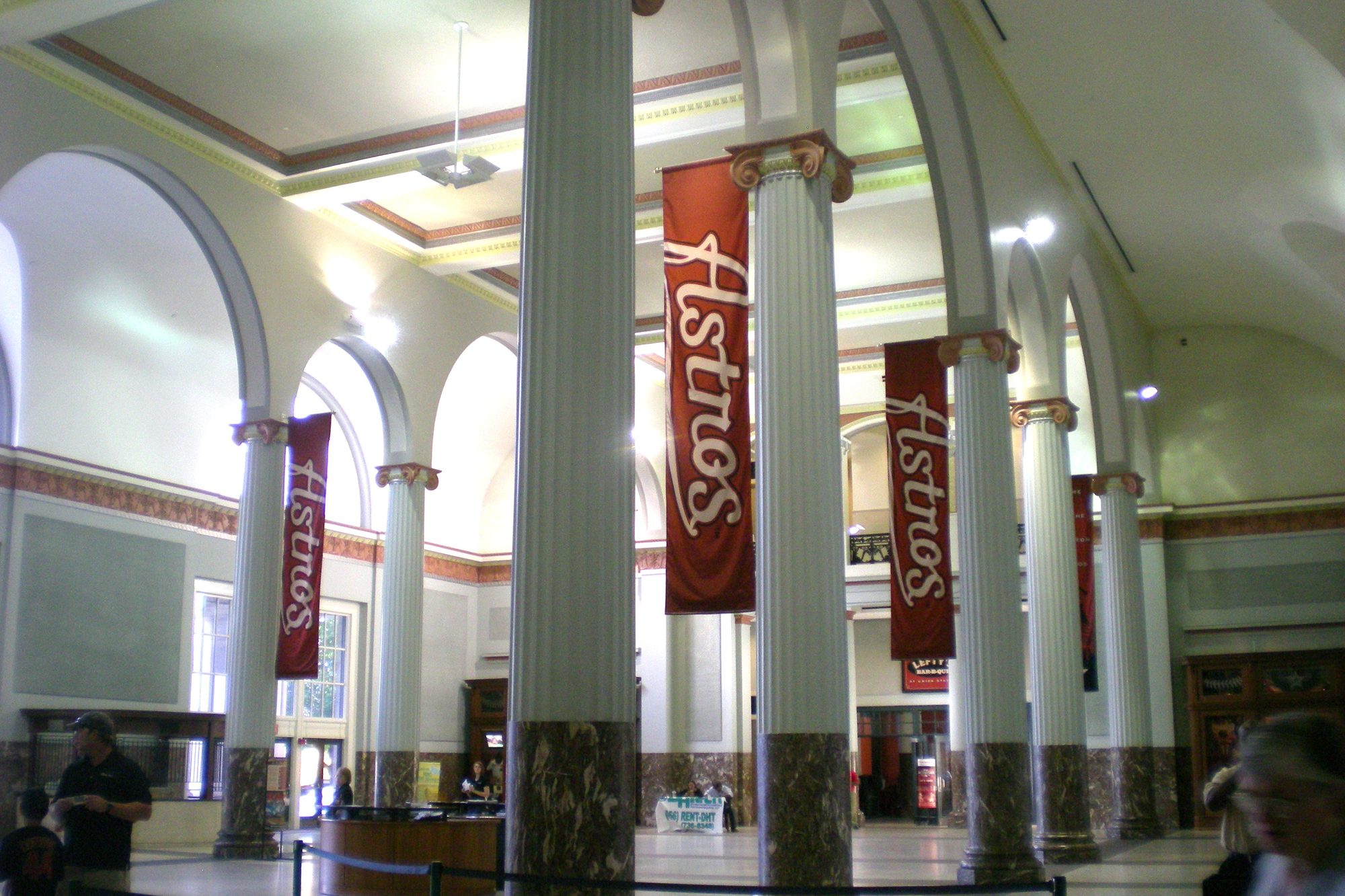 The marble-columned lobby of the 1911 Union Station head house built into Daikin Park, with tall Astros banners hanging between the arches