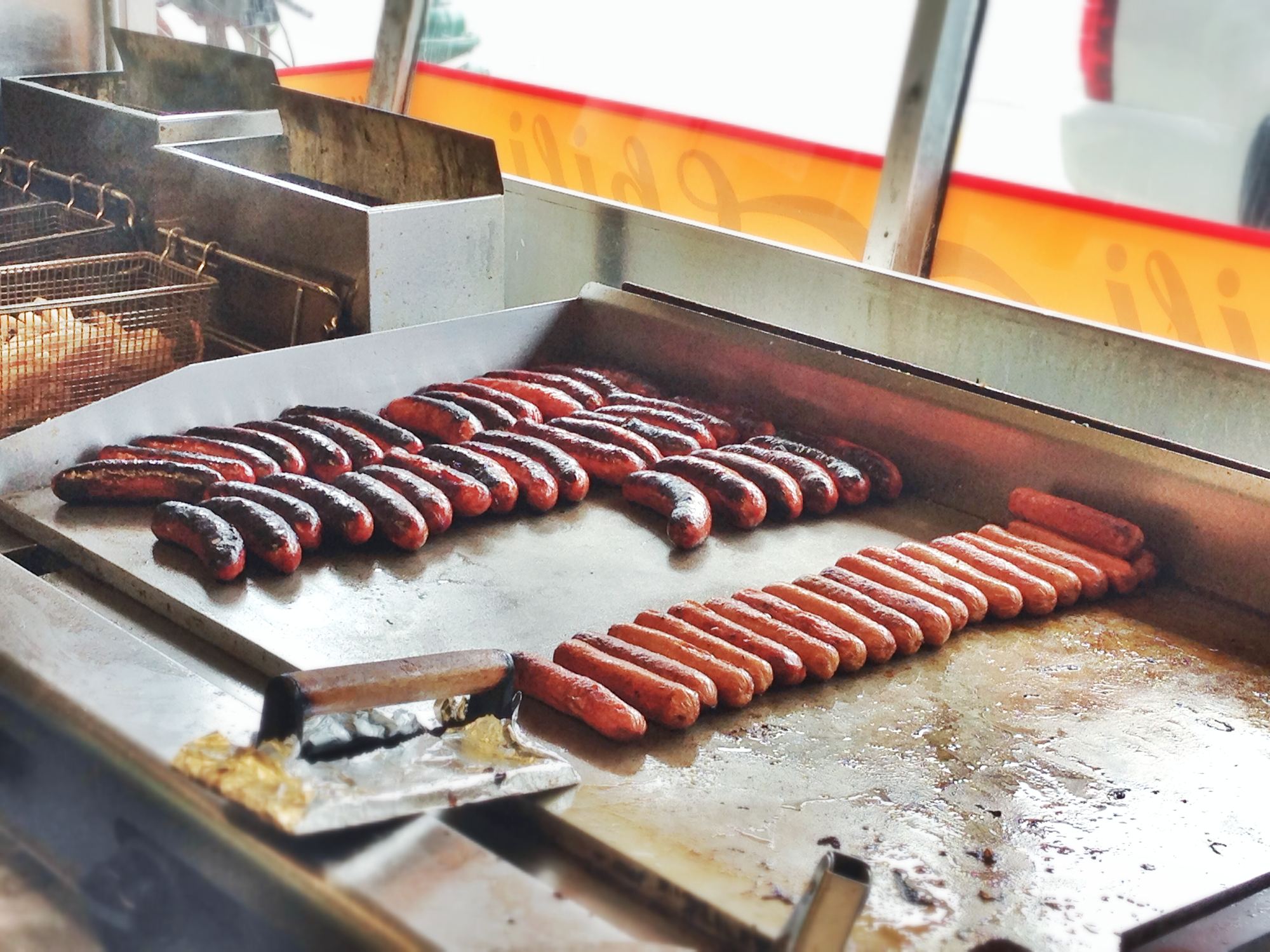Half-smokes and hot dogs cooking on a flat-top griddle
