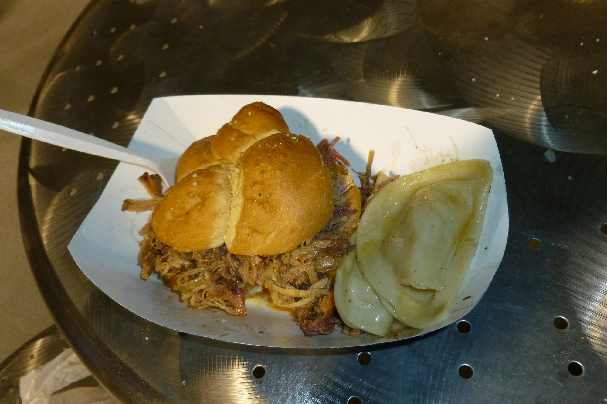 A pulled pork sandwich on a soft roll and a single pierogi in a paper concession tray at PNC Park