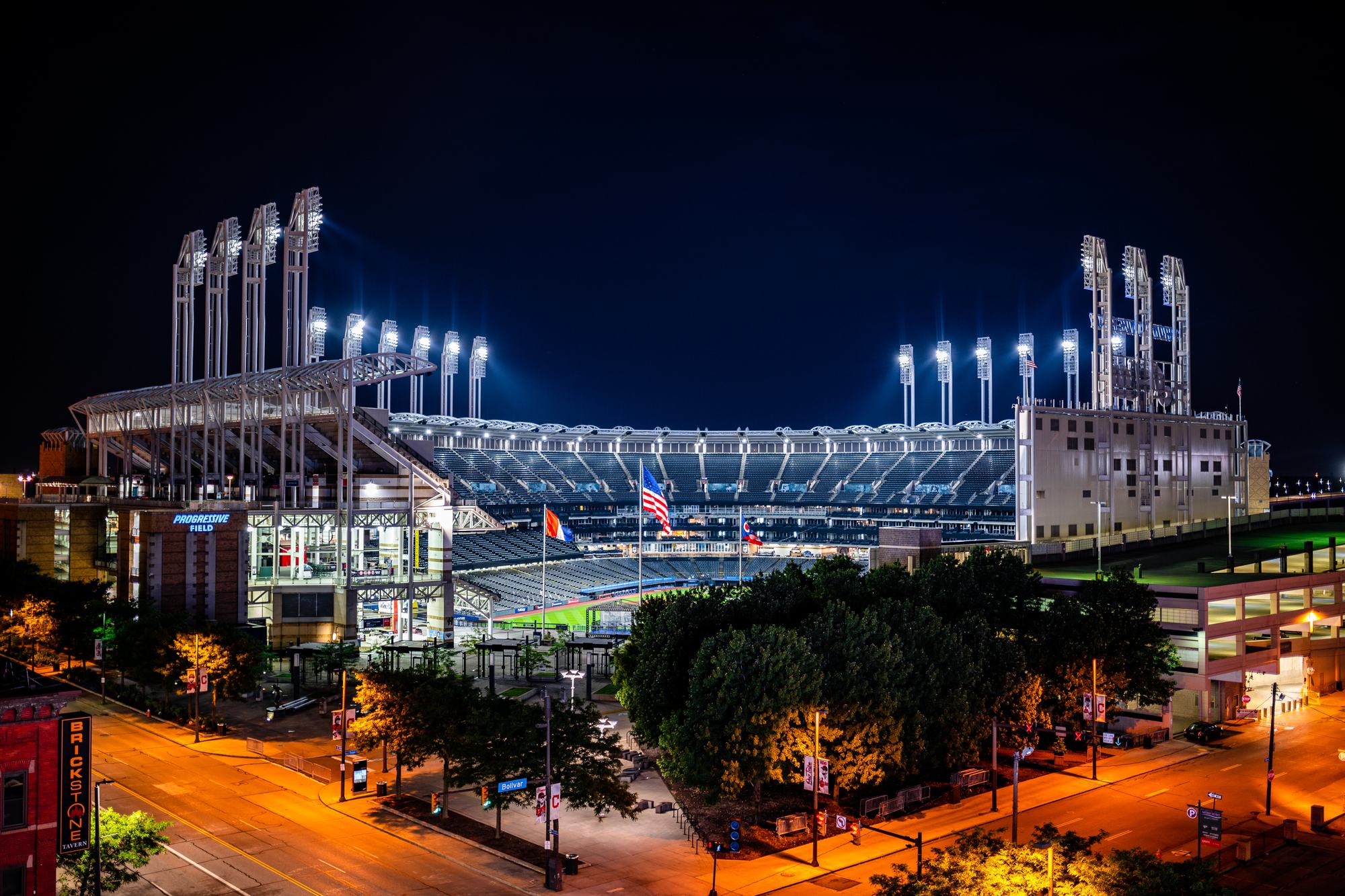 Progressive Field lit for a night game, the light towers and the bowl glowing against the downtown Cleveland skyline