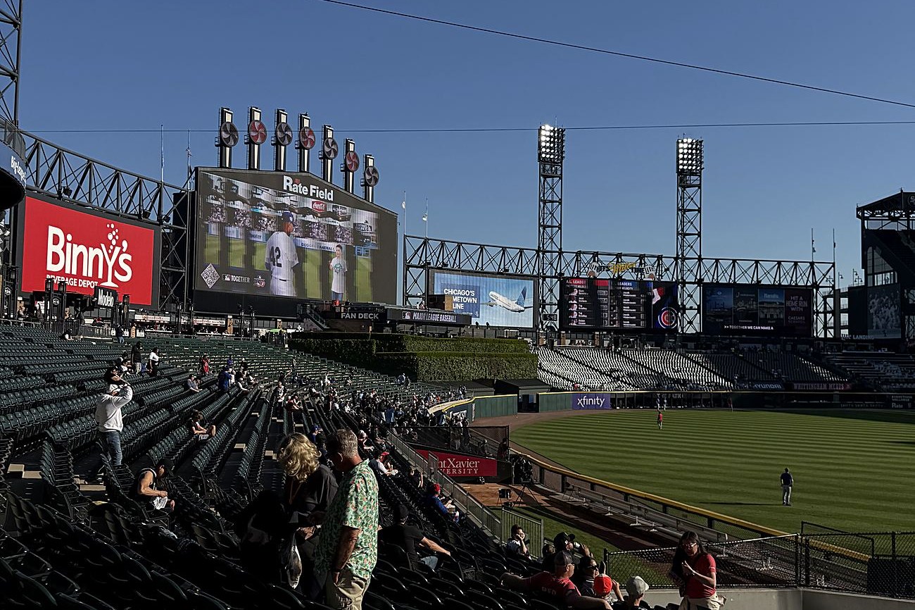 The seating bowl and outfield at Rate Field on a clear day, the center-field scoreboard above the bleachers