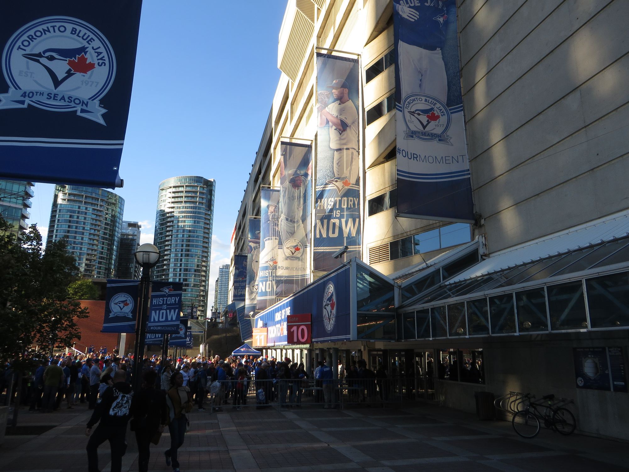 Fans outside Rogers Centre before a Blue Jays game, with team banners hanging on the building