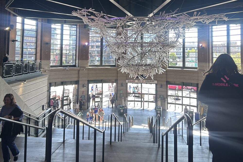 Stairs leading down to the entry turnstiles at the Center Field Gate of T-Mobile Park, under a chandelier made of translucent baseball bats