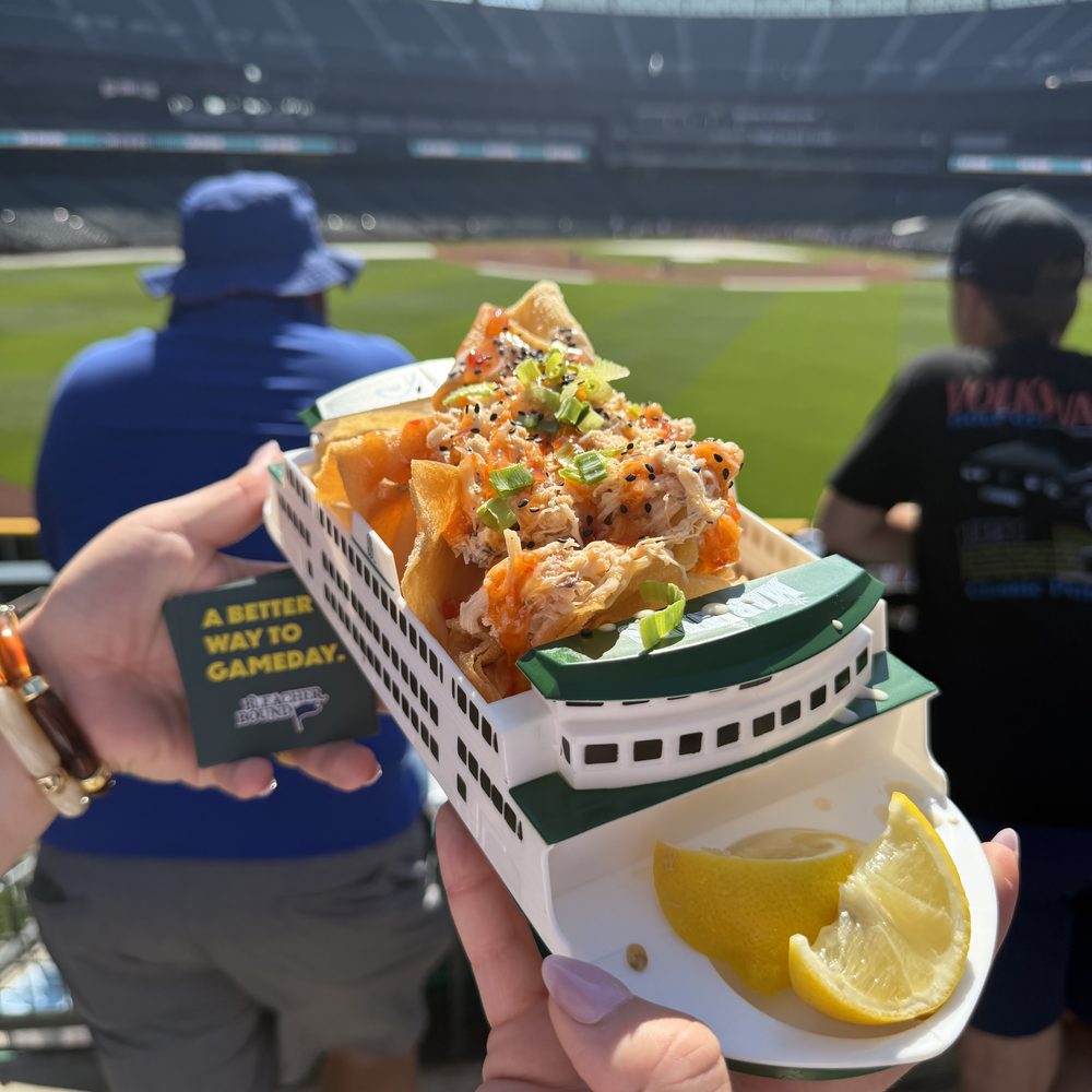 Crab nachos on wonton chips served in a plastic Washington State Ferry boat, held up over the outfield at T-Mobile Park