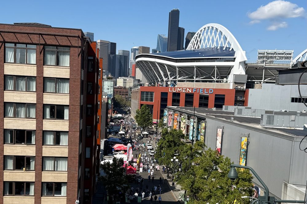 Lumen Field and the downtown Seattle skyline seen from T-Mobile Park, with crowds walking on the street between the two stadiums