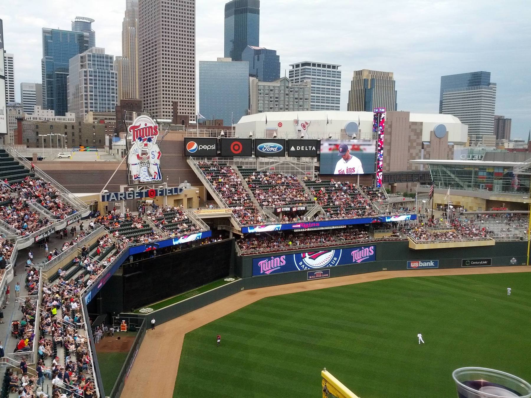 The downtown Minneapolis skyline beyond the outfield at Target Field, with the scoreboard above the seats